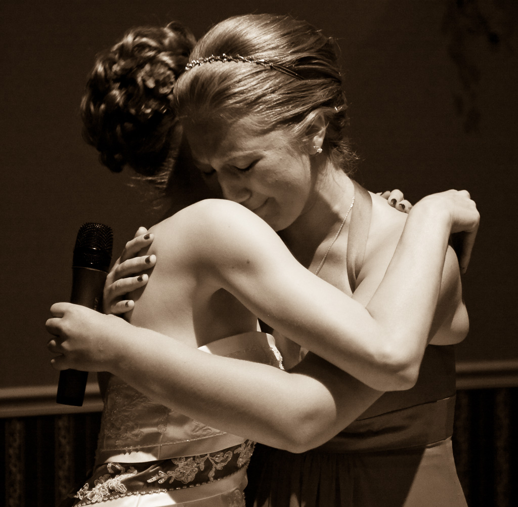 Photograph of a bride and maid of honor hugging