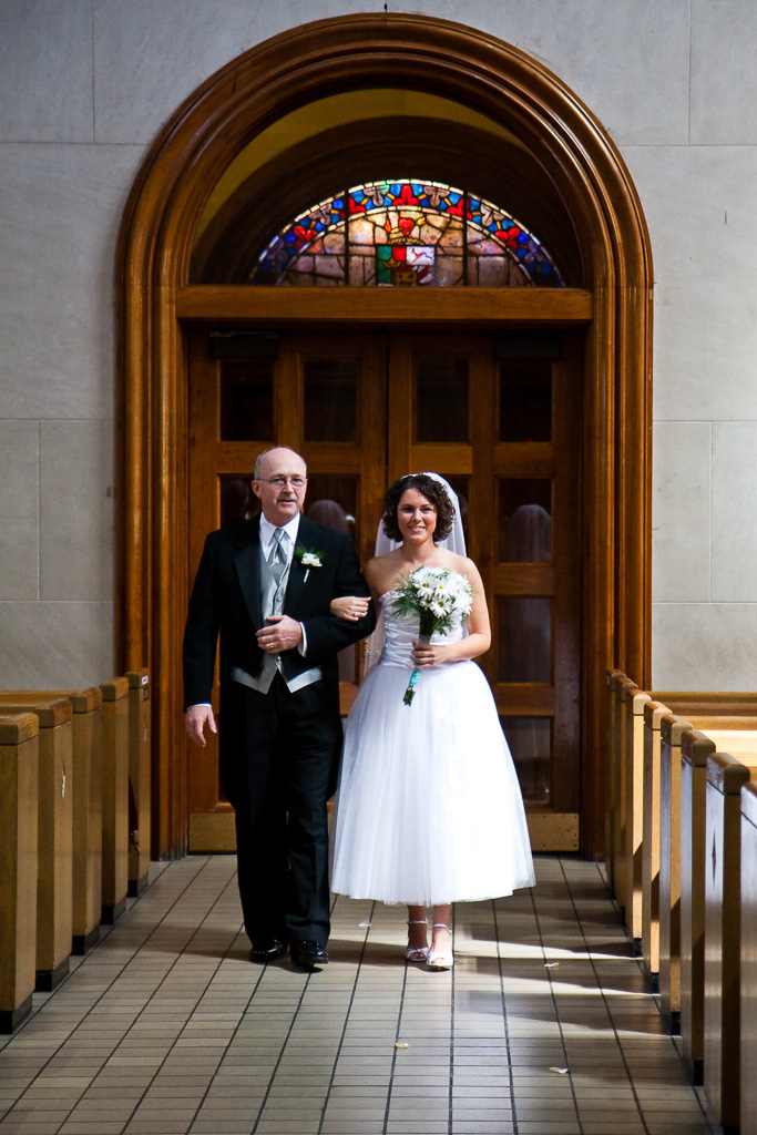 Photograph of a bride and her father walking down the isle in a church