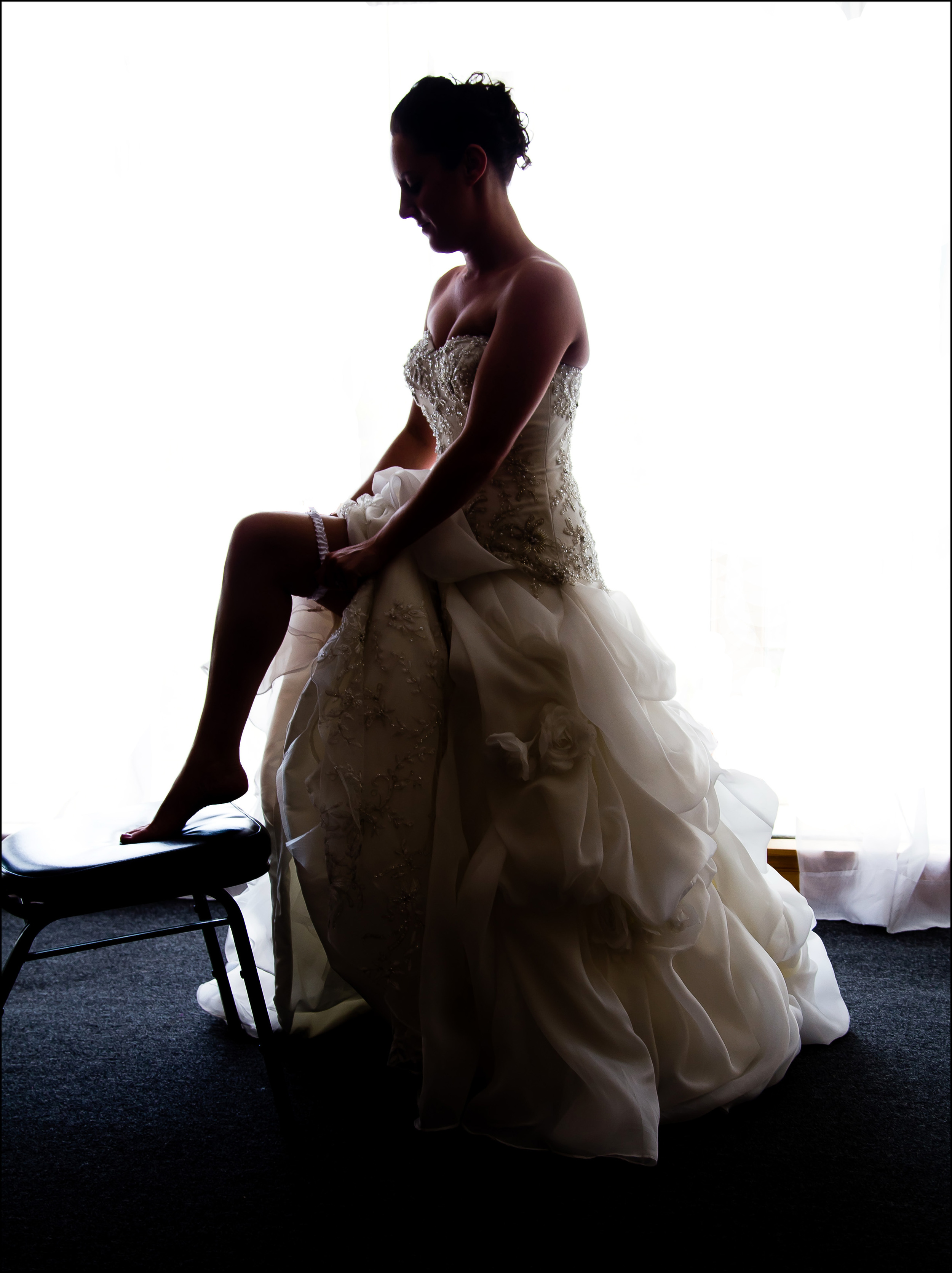 Candid photograph of a bride putting on garter